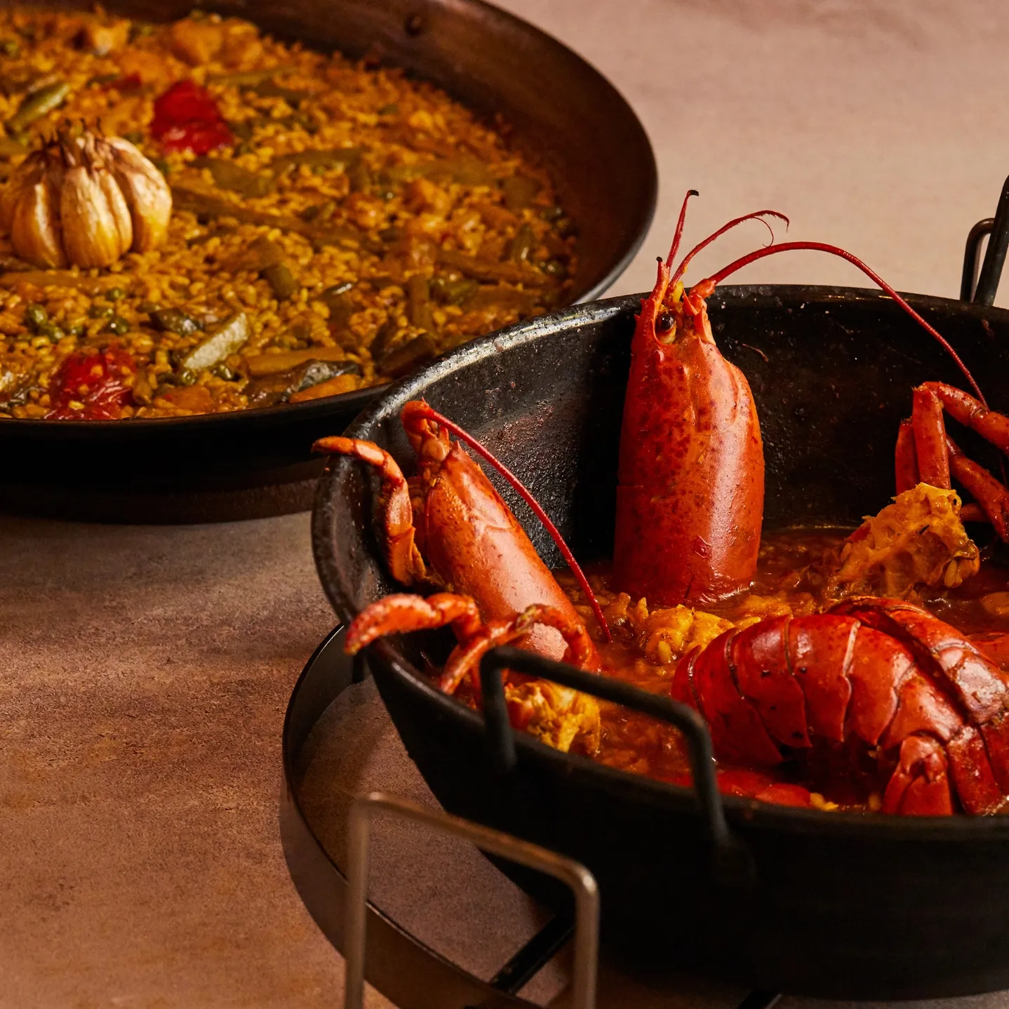 Creamy lobster rice in a paella pan with the whole lobster