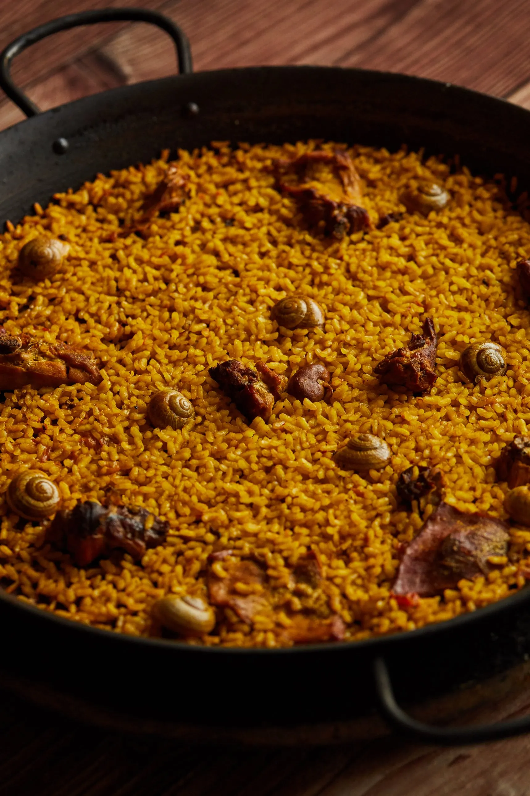 Paella de conejo y caracoles en paellera de hierro