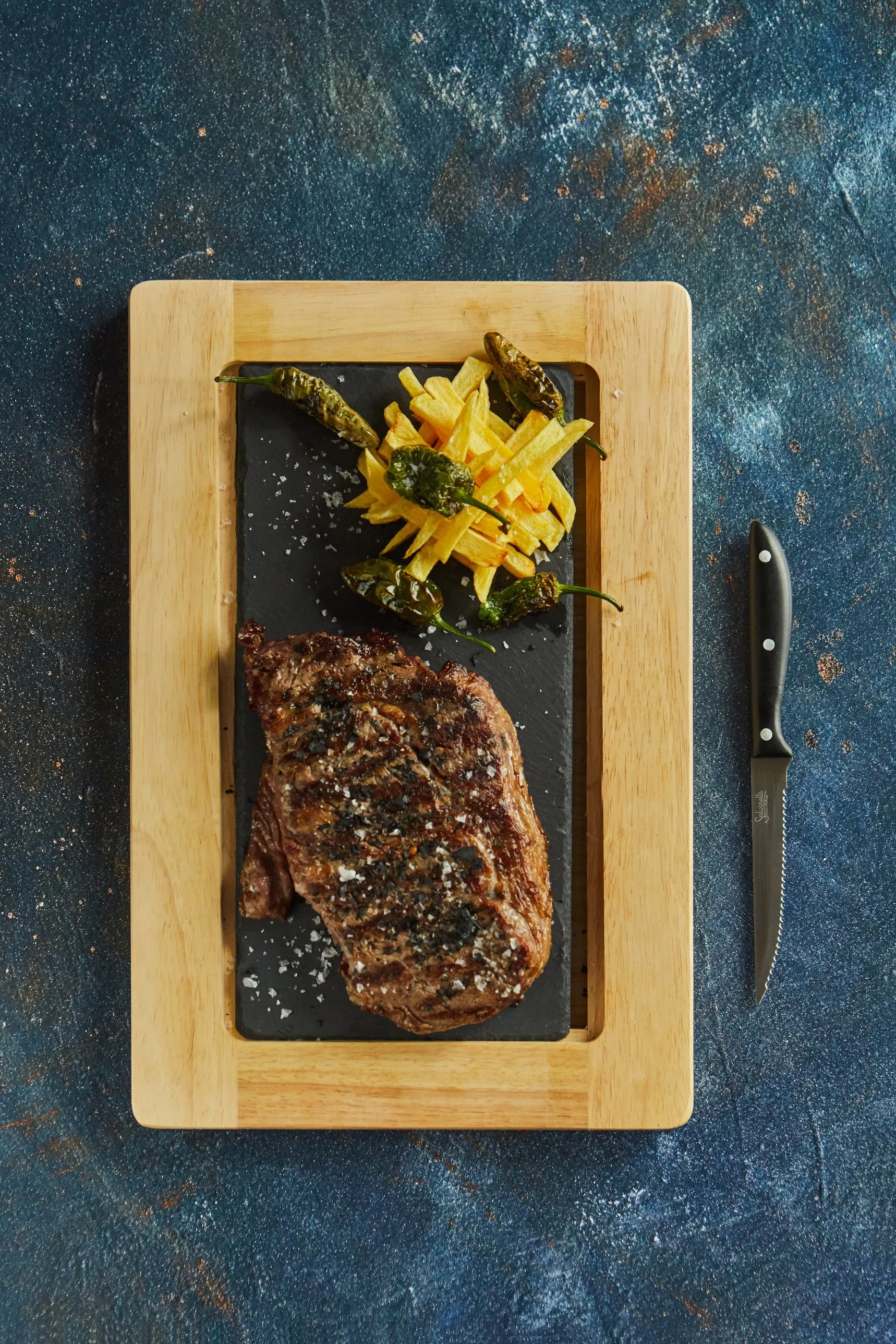 Carne a la brasa con sal en escamas, patatas y pimientos, vista desde arriba