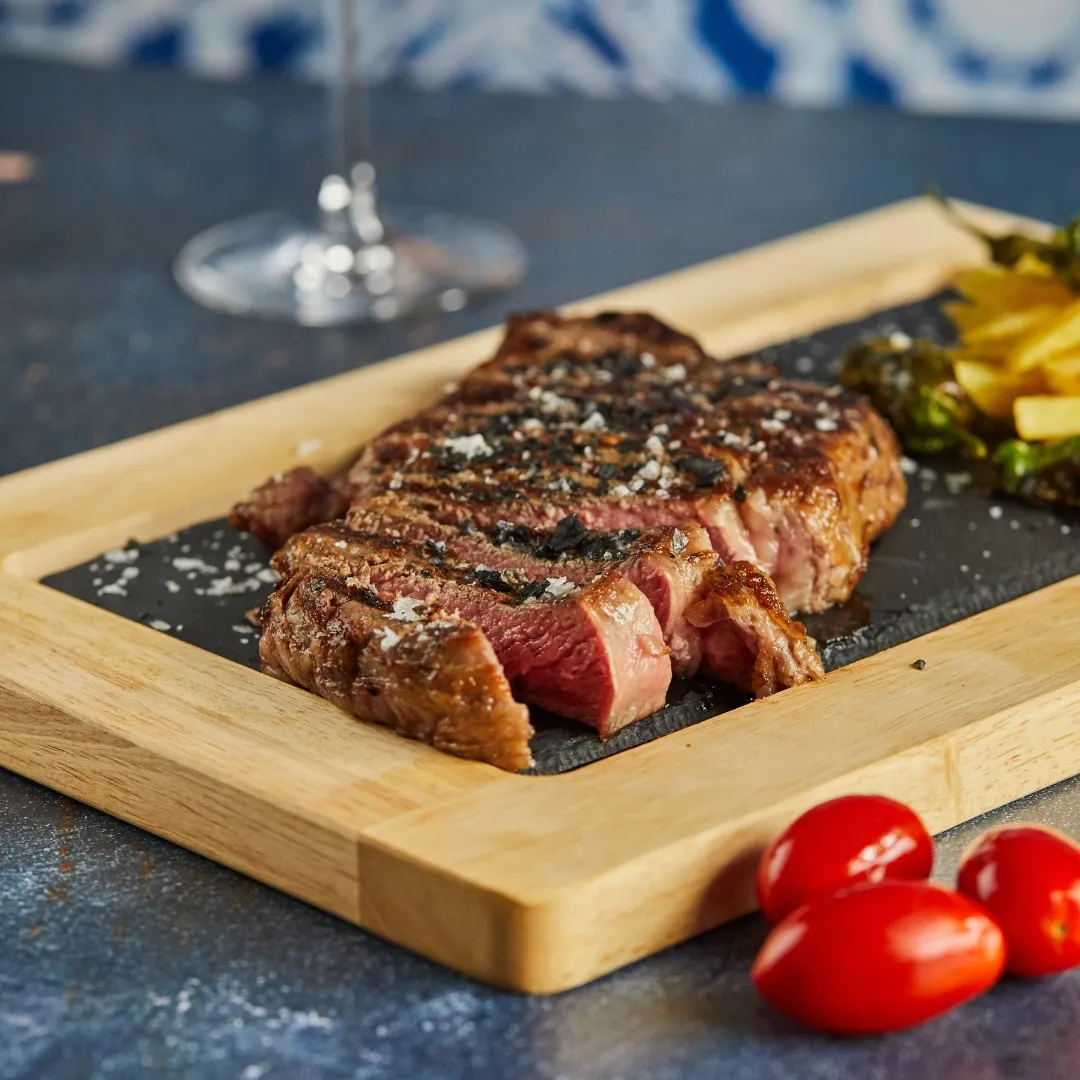 Chuletón a la brasa cortado sobre tabla de pizarra