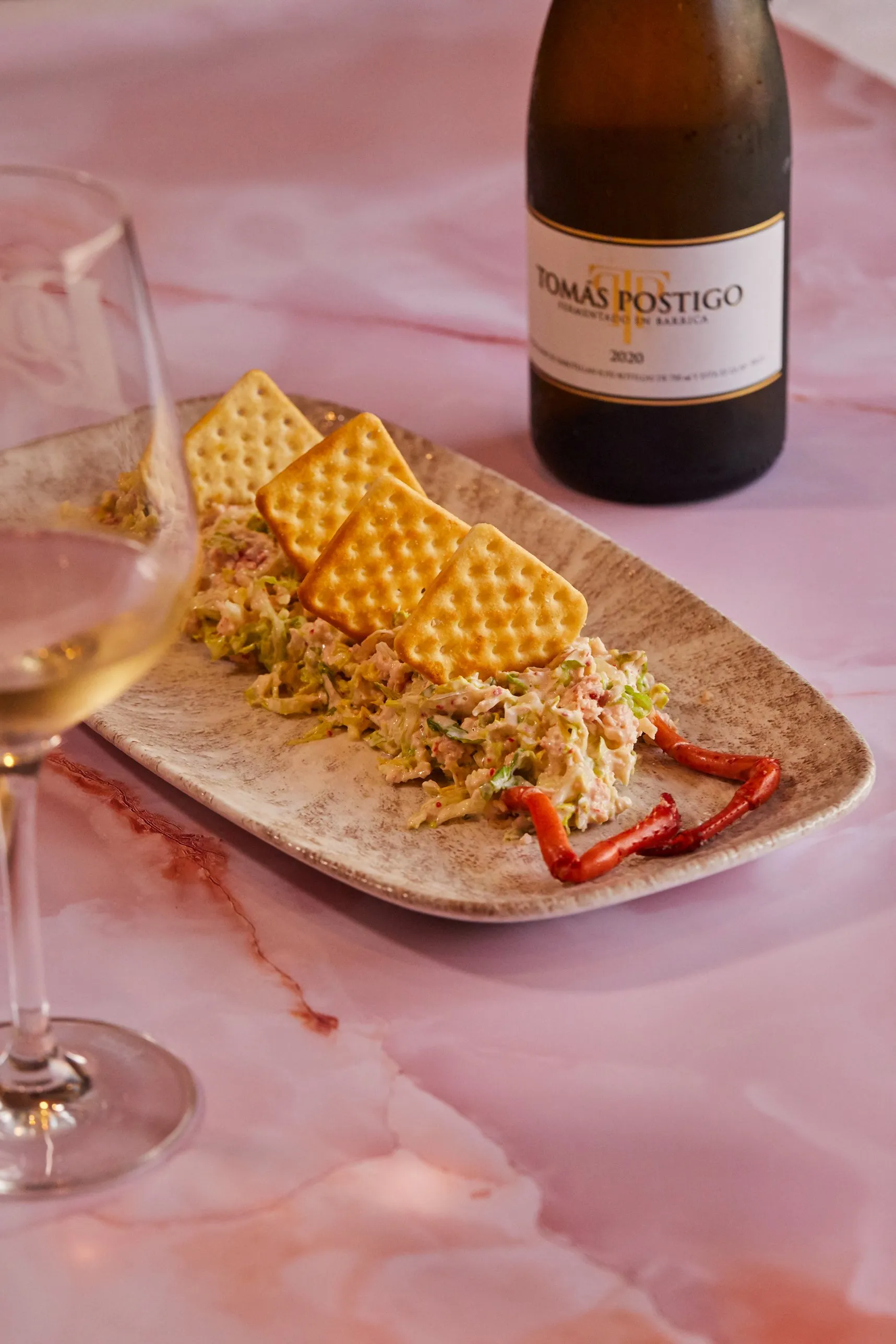 Lobster salad with crackers, a glass and a bottle of white wine