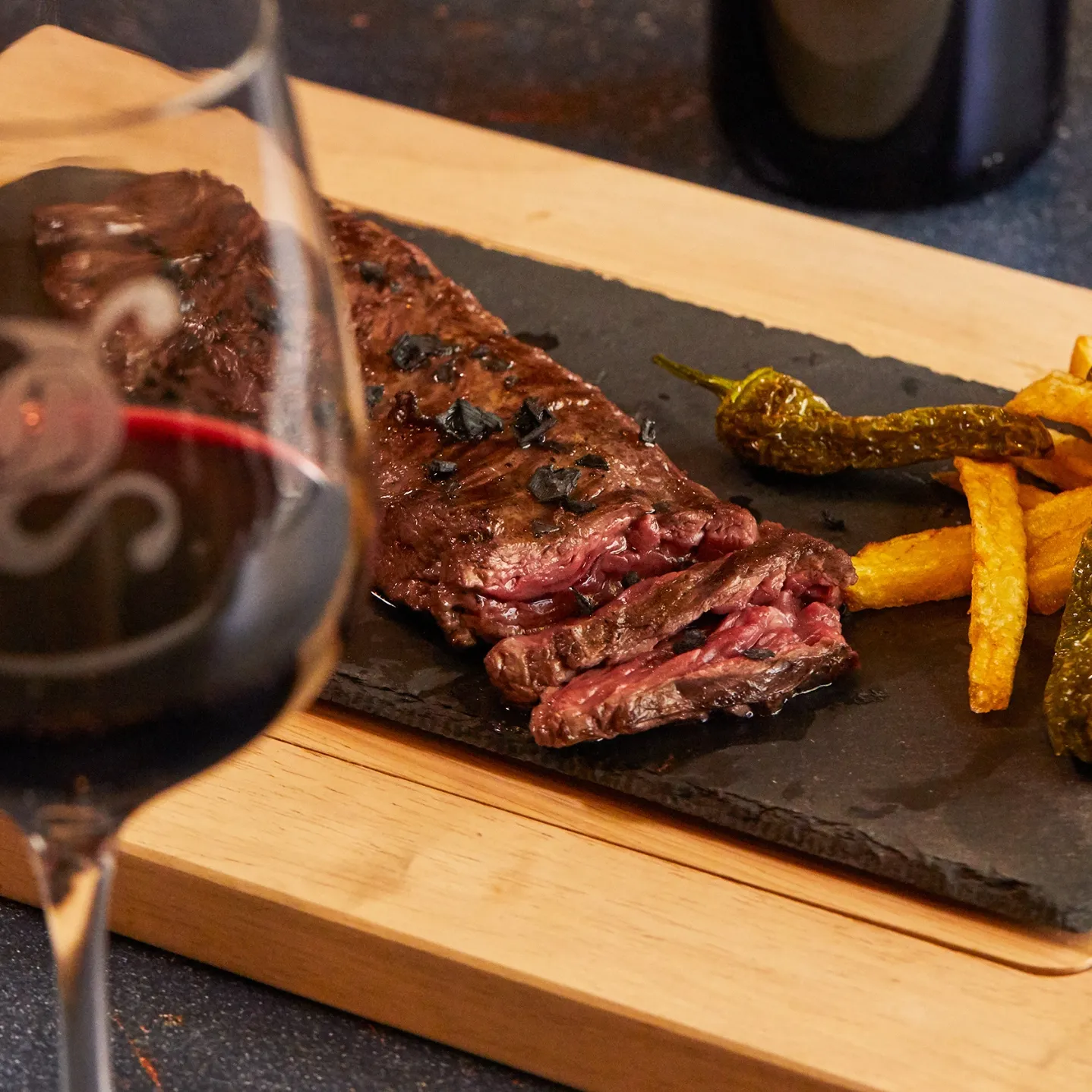 Chargrilled wagyu skirt steak on slate with peppers and chips